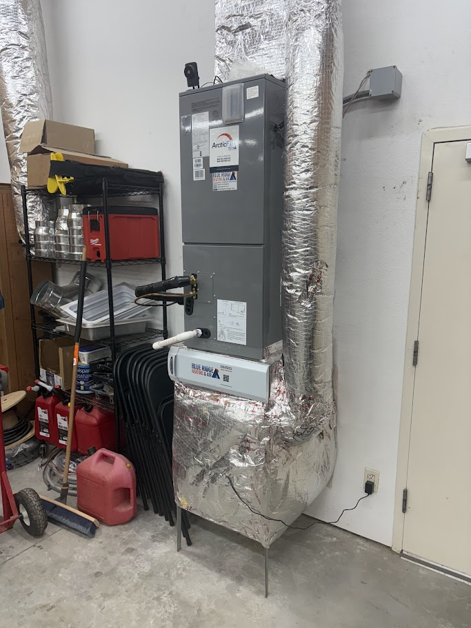 Indoor ArcticFlex air handler unit installed in a utility room with insulated ductwork and a Blue Ridge Heating & Air branded service sticker on the front