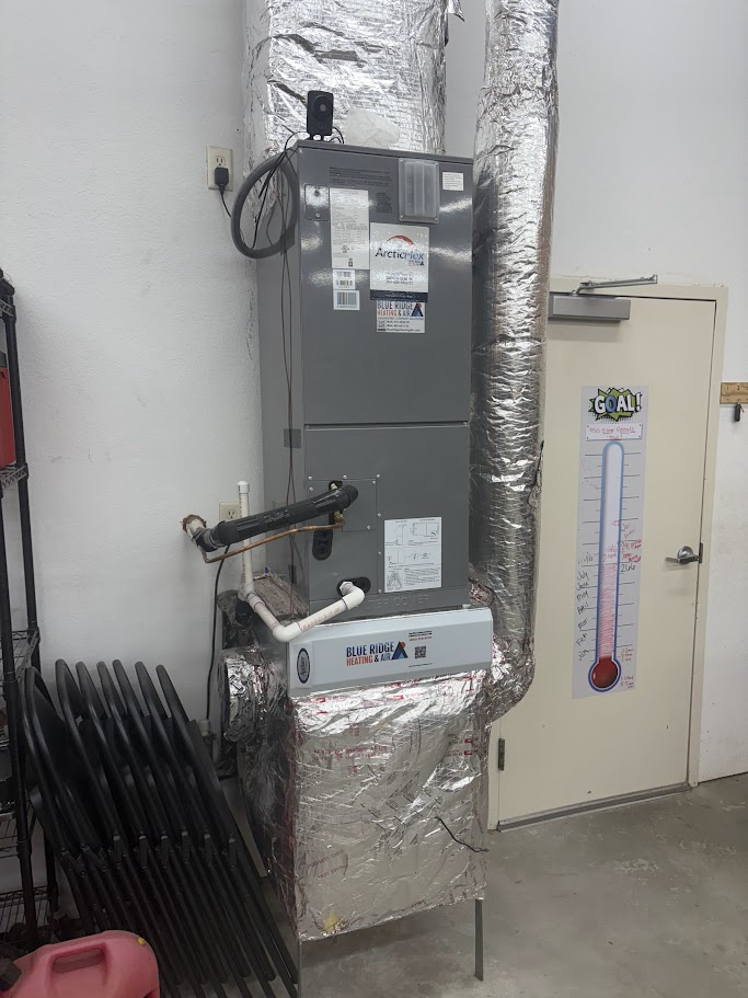 Indoor ArcticFlex air handler unit installed in a utility room with insulated ductwork and a Blue Ridge Heating & Air branded service sticker on the front