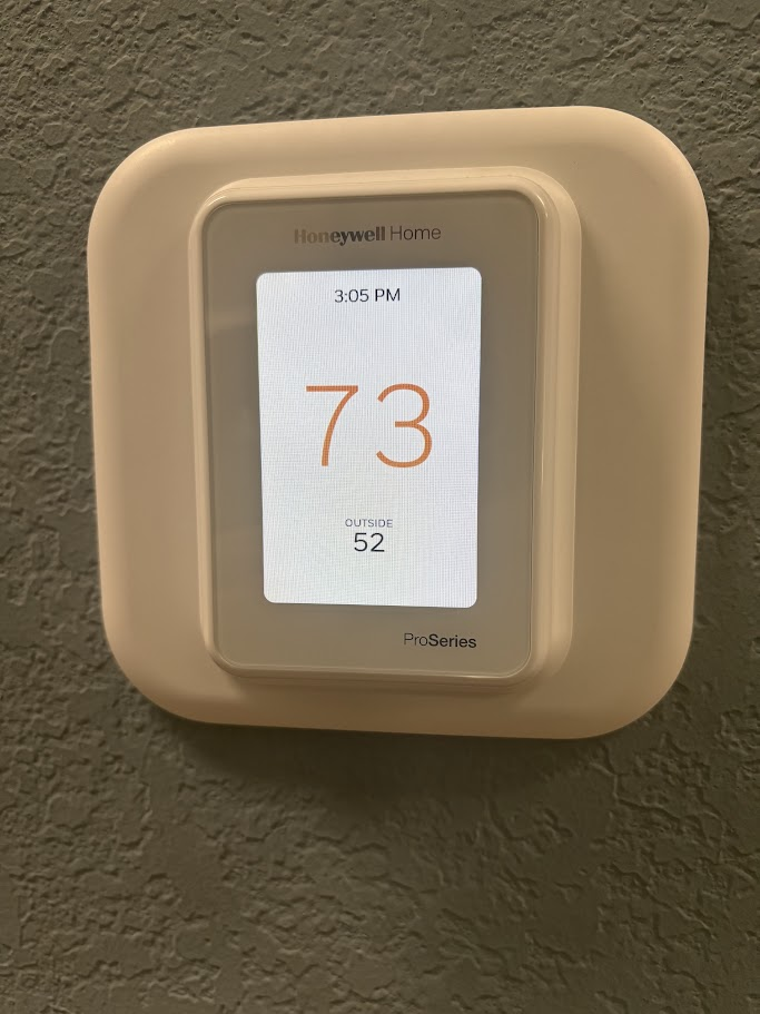 Honeywell Home T10 Pro Series smart thermostat mounted on a wall, displaying an indoor temperature of 73 degrees and an outside temperature of 52