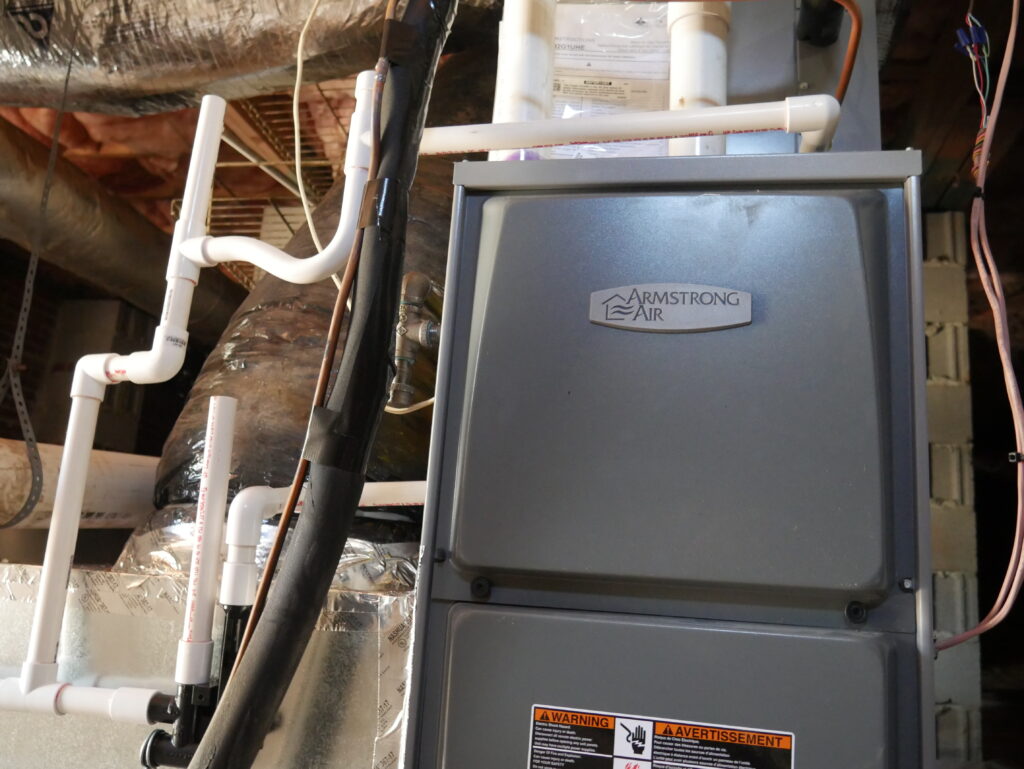 Armstrong Air indoor gas furnace connected to ductwork with PVC venting in a crawl space
